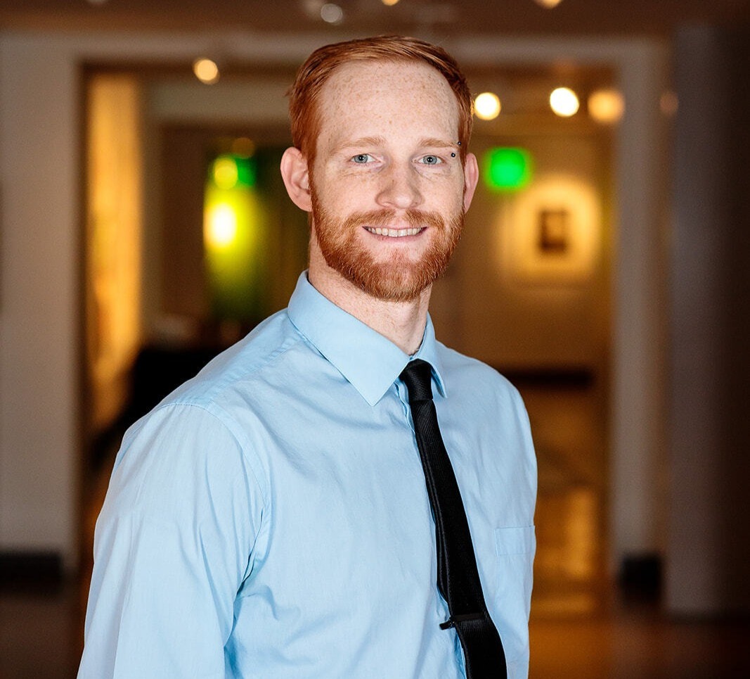 Daniel Armstrong wearing a blue shirt and black tie.